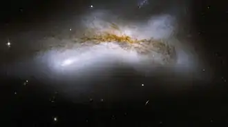 On peut voir sur la photo une vieille queue d'étoiles et un ruban dominant de poussière qui obscurcit la galaxie. (Télescope spatial Hubble)