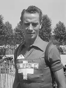 Photographie en noir et blanc d'un cycliste portant un maillot marqué d'une croix suisse et de l'inscription La Perle.