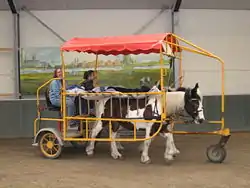 Cheval de profil avec un lit à roulettes sur le dos.