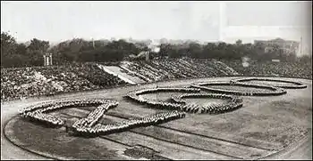 Photo noir et blanc de groupes d'individus formant le nombre 2600 sur la pelouse centrale d'un stade.