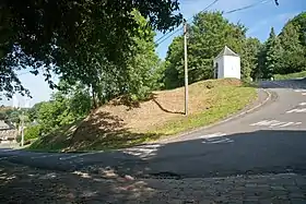 Vue d'une ascension cycliste et d'un virage vers la gauche. Une chapelle est visible sur l'image.