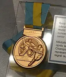 photographie d'une médaille en or avec un ruban bleu et jaune