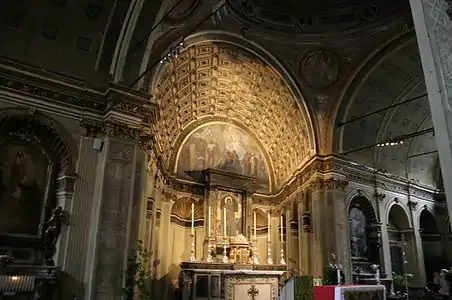 Image photographique d'un chœur d'abside en trompe œil avec une voûte en berceau à caissons composée de trois arcs de la même manière que la salle et se termine dans une illusion de perspective par une contre-façade dans les parties latérales de laquelle se trouvent deux niches et dont la lunette est peinte à fresque.