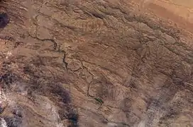 Vue d'un désert avec une rivière coupant l'image en deux.