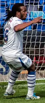 un footballeur dans un maillot blanc devant un filet de cage de football