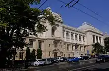 façade néo-classique alternant symétriquement des arcades droites et des travées cintrées sur trois niveaux : les deux premiers présentent une maçonnerie à bossages gris pâle, le troisième une façade enduite de blanc