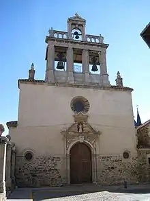 Photo de la façade blanche d'un église, avec clocher-porche ajouré, sous un ciel bleu