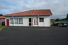 Petit bâtiment rouge et blanc proche d'un champ.