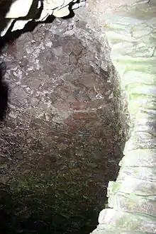 Vue en contre-plongée zénithale d'une voûte en encorbellement. À droite, un mur de soutien.