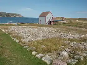 Une maison de pêcheur sur l'île aux Marins, avec la côte de l'île de Saint-Pierre en arrière plan.