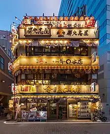 Façade éclairée d'un restaurant de 3 étages avec des panneaux japonais et des lanternes en papier rouge, à Yūrakuchō. Juin 2019.