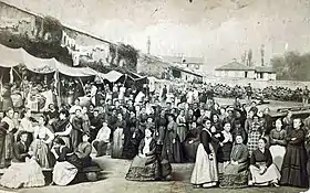 Photomontage sépia montrant une foule de femmes occupées à diverses activités, fixant l'objectif du photographe, dans une large cour ceinte de hauts murs. Un soldat en faction à l'arrière-plan les surveille.