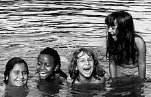 Photo en noir et blanc représentant quatre petites filles jouant dans l'eau.