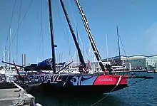 Bateau noir vu de trois quarts avant. Avant rouge et motif argenté représentant une tête de bœuf.