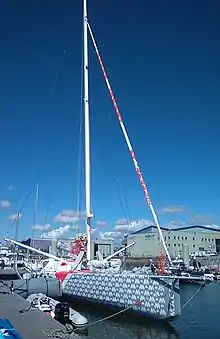 Voilier gris amarré au ponton, vu de trois quarts avant.