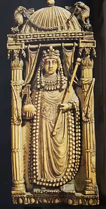 Photographie d'une pièce ouvragée représentant une femme en tenue d'impératrice sous un chapiteau supporté par deux colonnes.