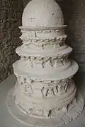 Petit stupa votif, recouvert de stuc, couronnes superposées décroissantes surmontées d'un stupa hémisphérique. Décor : pilastres et niches à bouddhas, à pans obliques.