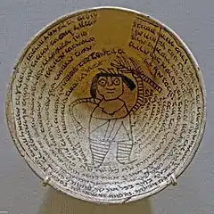 Coupe de terre cuite, décorée de lignes d'écritures concentriques. Au centre une figure antrophomorphe.