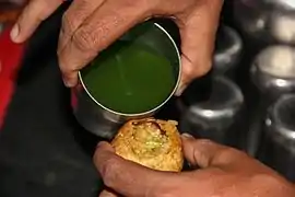 Du chutney vert versé dans un pani puri.
