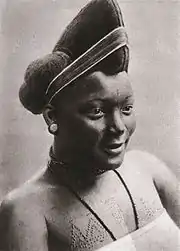 photo noir et blanc d'une femme avec une coiffure tressée en hauteur et portant des scarifications sur le haut de la poitrine