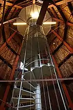 Un escalier en colimaçon au sein d'une structure en bois.