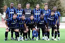 Photographie montrant onze joueurs de football alignés sur deux rangs, vêtus de tenues bleues et noires