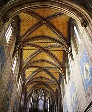 Voûtes gothiques d'une église richement ornée ; au fond, un orgue sur tribune.