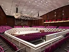 salle de concert avec les fauteuils et la scène et un orgue en arrière-plan