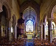 Photographie d'un chœur d'église en vue axiale, séparé en deux par un arc diaphragme et ouvert par une baie à son extrémité