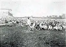 Dans un hippodrome, une foule de Coréens sont assis dans l'herbe.