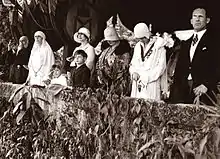 Photo noir et blanc d'un groupe de personnes debout en ligne derrière un muret bas.