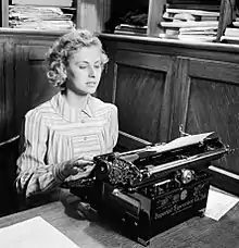 photographie en noir et blanc d'une femme devant une machine à écrire