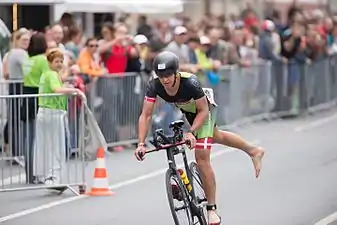 Un triathlète s’apprête à descendre de son vélo.