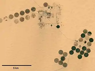 Système d'irrigation circulaire à pivot central, dans le cœur du Sahara, avec prélèvement dans une nappe fossile (qui ne pourra pas se recharger). Ce système gaspille beaucoup plus d'eau qu'un système de type goutte à goutte. (Imagerie satellitaire : NASA)