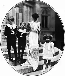 revêtue d'une robe longue de teinte claire, la reine se tient debout aux côtés de ses enfants vêtus en habits d'apparat : Léopold qui regarde vers la droite, Charles qui lui donne le bras et Marie-José qu'elle tient par la main