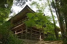 Un bâtiment en bois avec véranda entourant construit sur de grands piliers en bois.