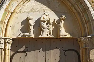 Tympan représentant la vierge à l'enfant entre deux chevaliers agenouillés.