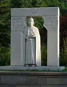 Statue blanche d'un roi portant une cape, un sceptre et une couronne.