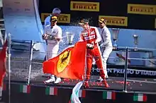 Photographie de pilotes célébrant leur podium en s'aspergeant de champagne.