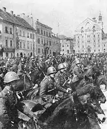 Un groupe de militaires à cheval, sur la place d'une ville.