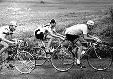 Photographie en noir et blanc montrant trois cyclistes lors d'une course.