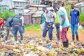 Jeunes gens, plus ou moins masqués, ramassant des déchets à Kibera.