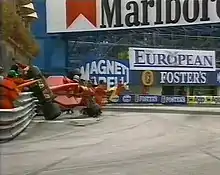 Photo d'une monoplace rouge en position verticale, en train de s'écraser contre un rail de sécurité