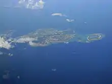 Vue aérienne couleur d'une île, dans une étendue d'eau bleue.