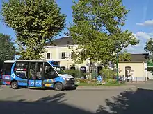 Photographie en couleurs d’un minibus devant la gare de Rumilly.