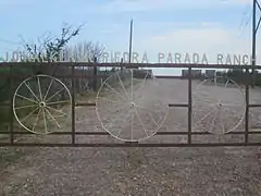 Le portail métallique d'une propriété dans lequel se trouvent trois roues de chariots.