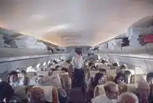 Intérieur d'un avion de ligne, montrant des rangées de six sièges, séparées en leur milieu par un couloir central.