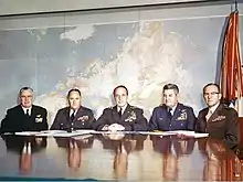 Un groupe de cinq hommes en uniforme militaire assis à une table.
