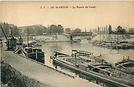 Le canal Saint-Denis, ouvert dès 1821, est la première infrastructure de transport performante qui irrigua la Plaine, à une époque où les transports par route étaient coûteux et lents. On voit ici le bassin de la Maltournée, avec des péniches déchargeant du charbon, sans doute destiné à l'usine à gaz du Cornillon.