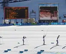 Skieurs passant devant le tableau des résultats lors d'une course de ski de fond